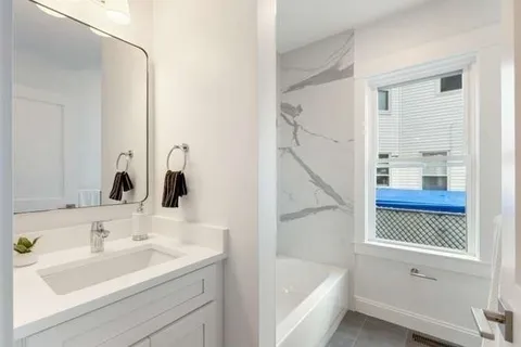a bathroom with a tub sink and mirror