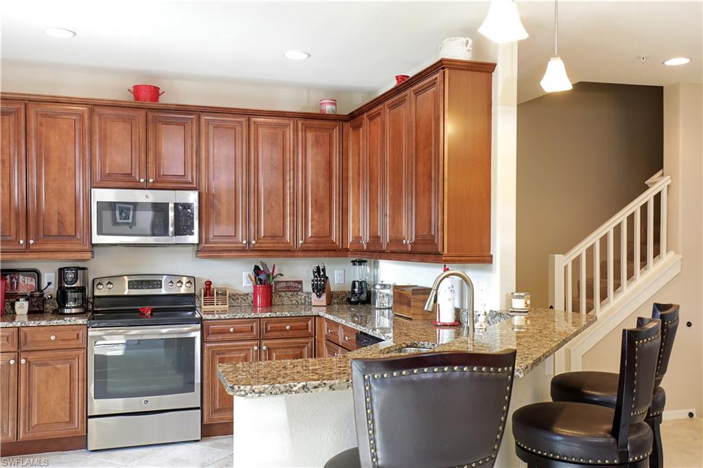 9051 Capistrano Street North, Unit 4308 Naples, FL 34113 - Photo 6 of 20 a kitchen with stainless steel appliances granite countertop a stove a sink and a microwave