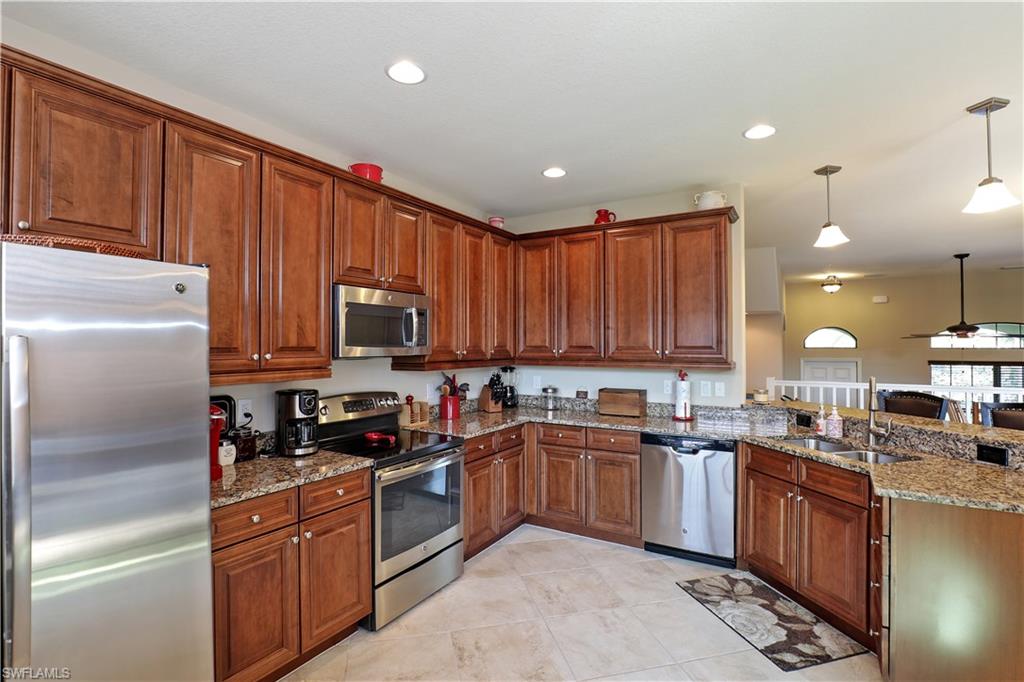 9051 Capistrano Street North, Unit 4308 Naples, FL 34113 - Photo 7 of 20 a kitchen with kitchen island granite countertop stainless steel appliances a sink a refrigerator and cabinets