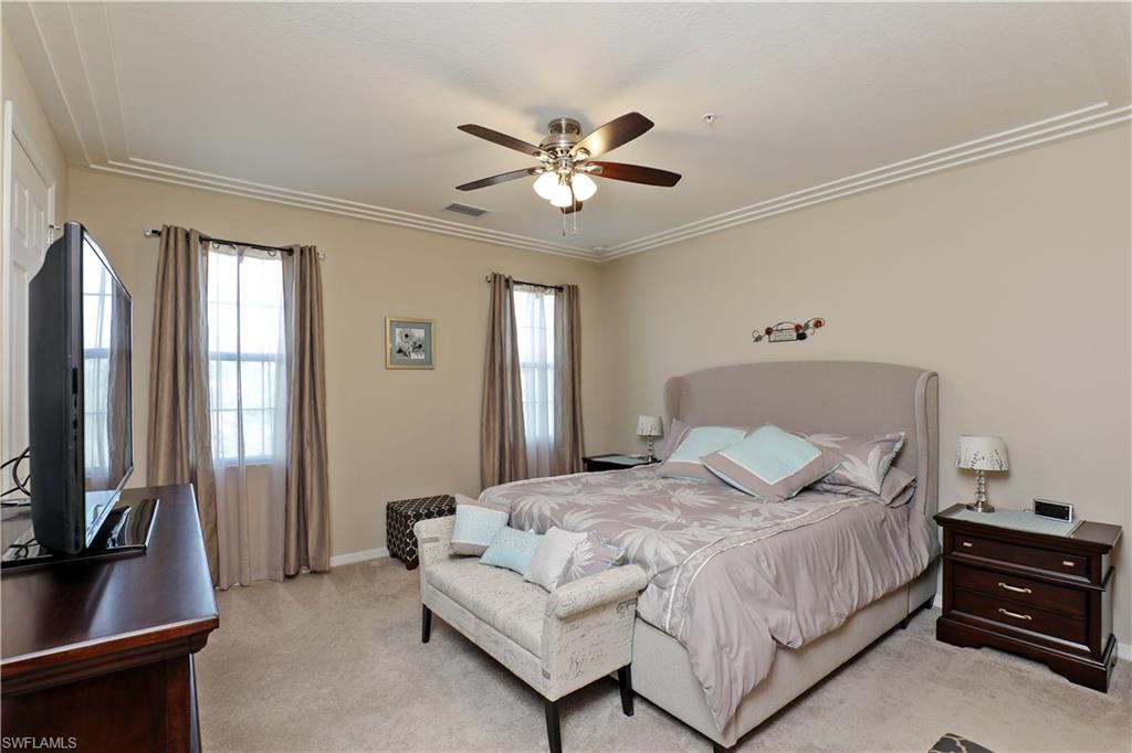 9051 Capistrano Street North, Unit 4308 Naples, FL 34113 - Photo 8 of 20 a bedroom with a large bed and a flat tv screen on a dresser