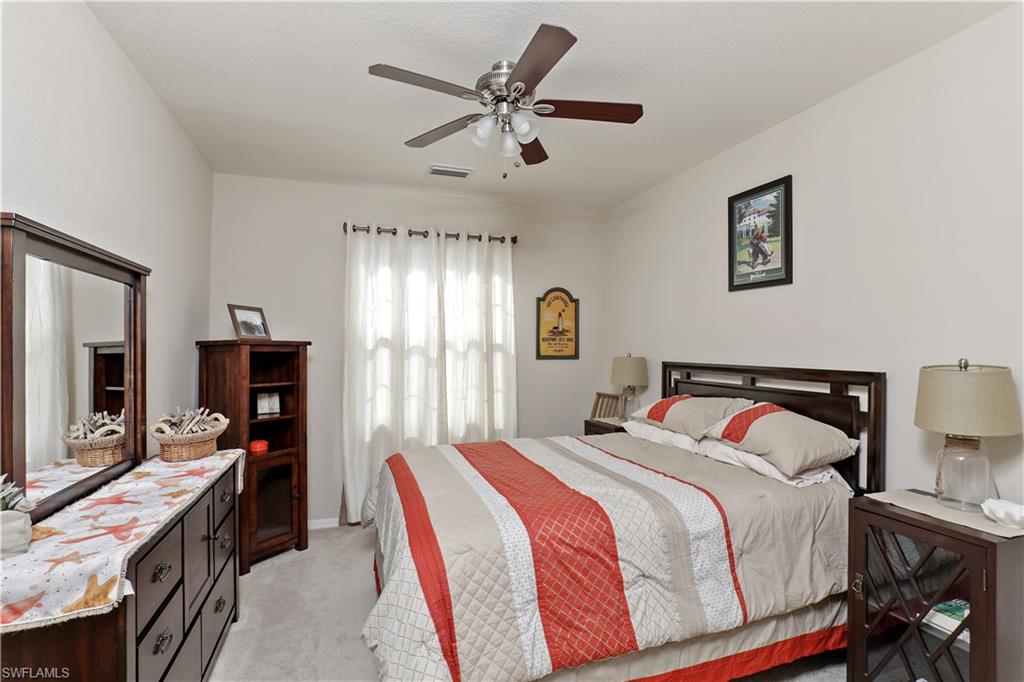 9051 Capistrano Street North, Unit 4308 Naples, FL 34113 - Photo 10 of 20 a bedroom with a bed and a flat tv screen on a dresser