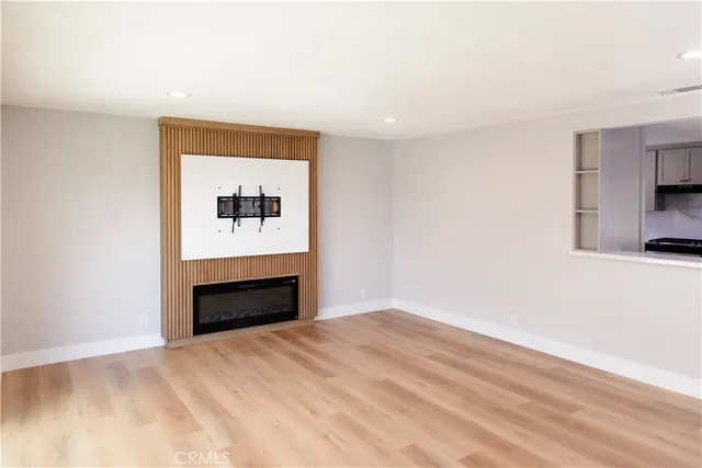 a view of an empty room with wooden floor and closet