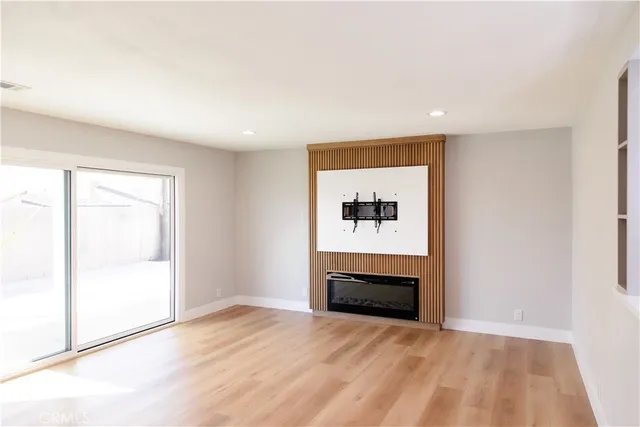 a view of an empty room with wooden floor and closet