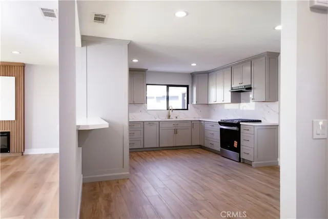 a kitchen with granite countertop a stove a sink and a refrigerator