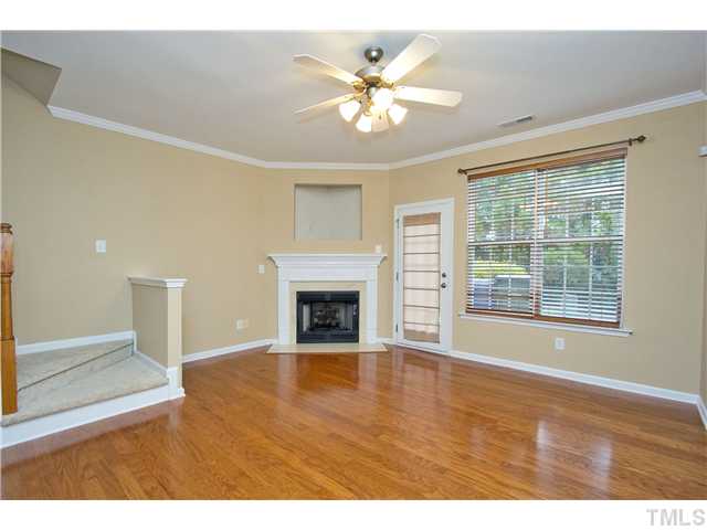 7843 Spungold Street Raleigh, NC 27617 - Photo 5 of 20 a view of an empty room with chandelier fan and fire place