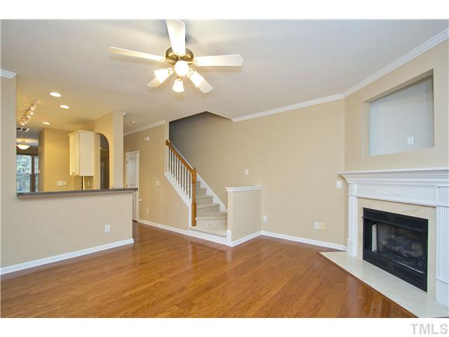 7843 Spungold Street Raleigh, NC 27617 - Photo 6 of 20 a view of an empty room with wooden floor and a fireplace