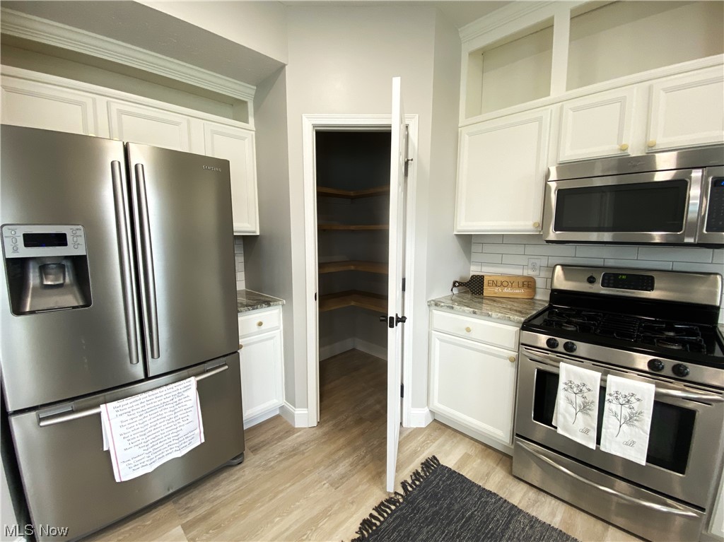 2113 Fowl Road Elyria, OH 44035 - Photo 12 of 39 Kitchen with appliances with stainless steel finishes, backsplash, and white cabinetry and walk-in pantry with custom shelving
