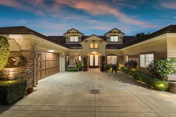 a view of a brick house with large windows and a small yard