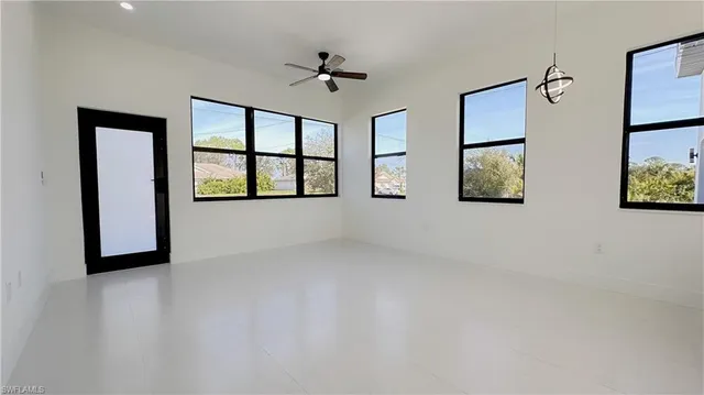an empty room with windows and ceiling fan