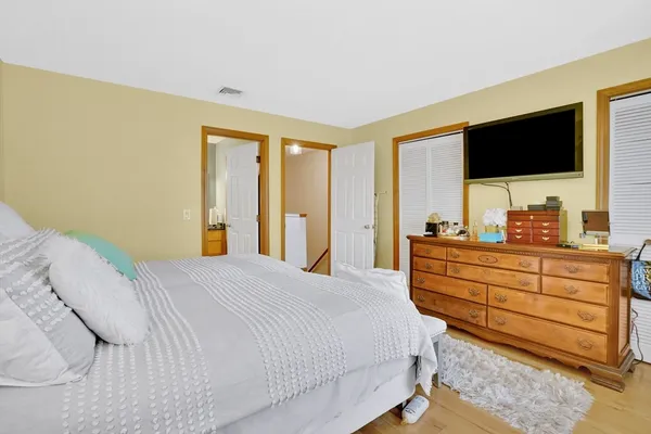 a bedroom with a bed and a flat tv screen on dresser