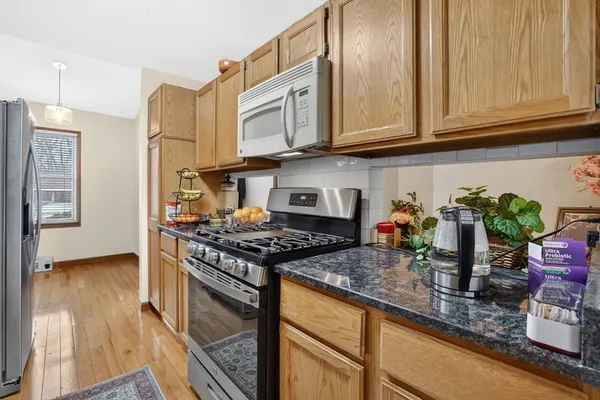 a kitchen with stainless steel appliances granite countertop a stove a sink dishwasher and cabinets with wooden floor
