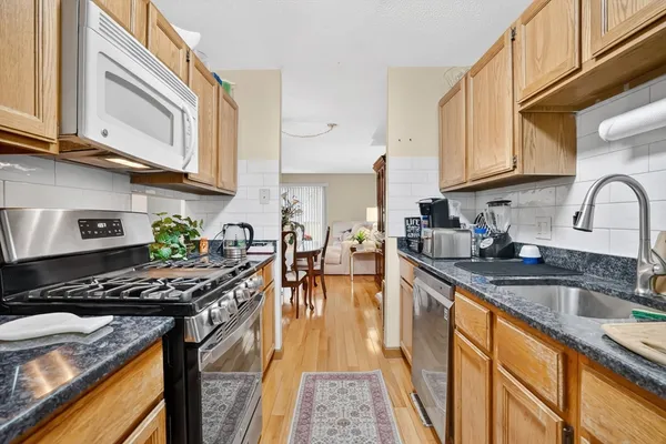 a kitchen with stainless steel appliances granite countertop a stove a sink dishwasher and cabinets with wooden floor