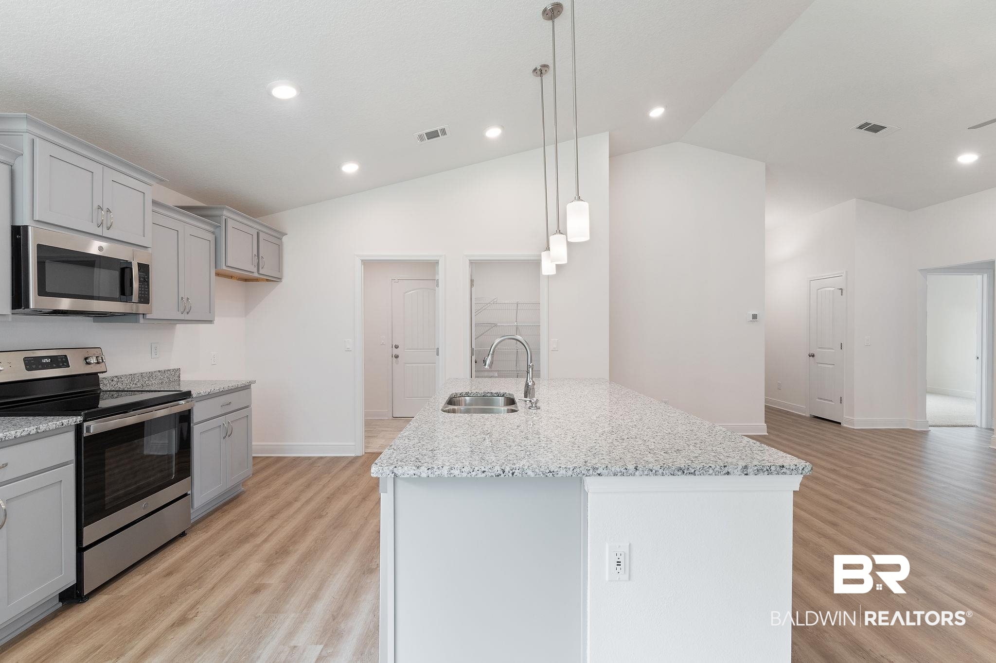 140 St Stephens Court Atmore, AL 36502 - Photo 4 of 14 Kitchen featuring a center island with sink, sink, appliances with stainless steel finishes, and vaulted ceiling