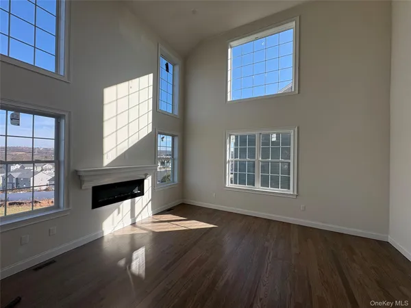 an empty room with windows fireplace and wooden floor