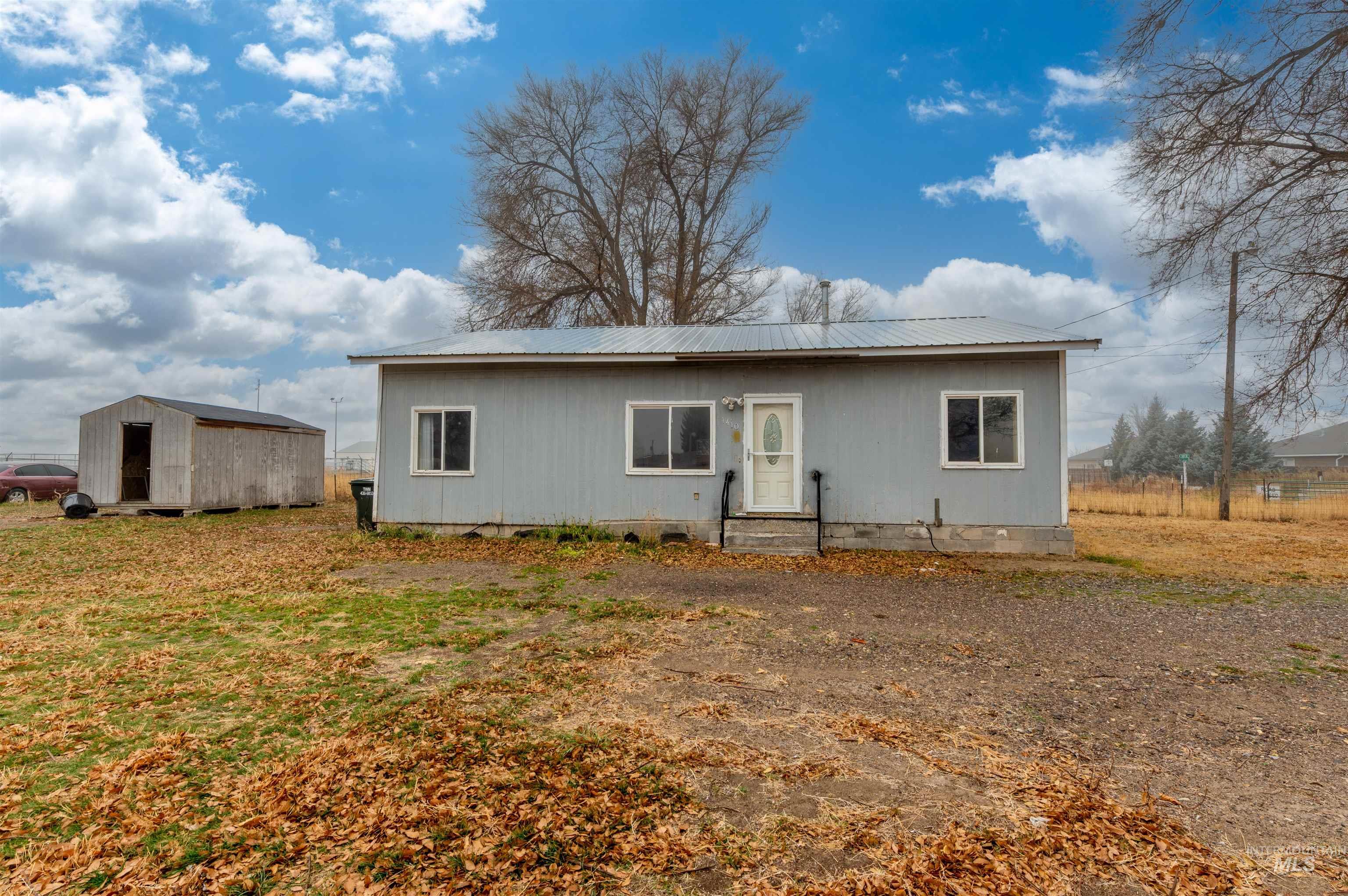 Back of property with a metal roof, crawl space, and a shed