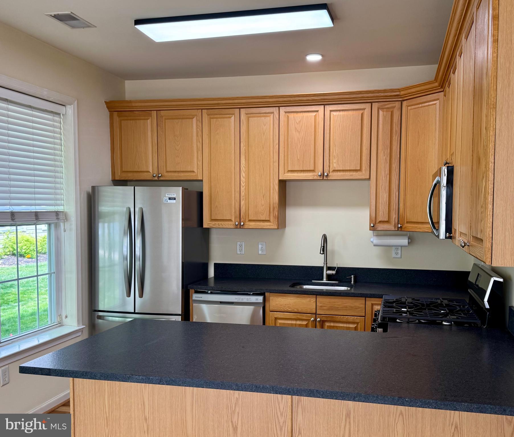 113 Kyle Way Ewing, NJ 08628 - Photo 20 of 25 a kitchen with stainless steel appliances granite countertop a refrigerator a stove and a sink with wooden cabinets