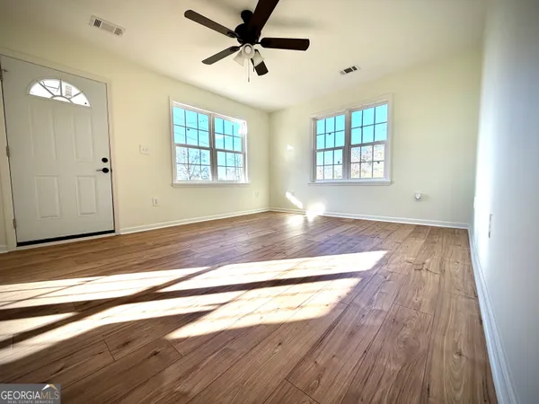 a view of empty room with wooden floor and fan