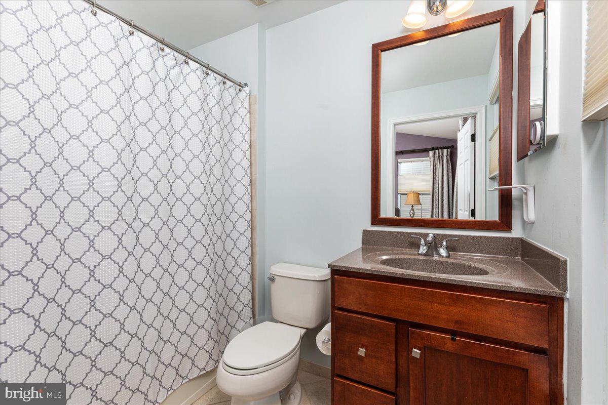 25436 South Riding Boulevard, Unit 2H Chantilly, VA 20152 - Photo 14 of 26 a bathroom with a granite countertop toilet and a sink