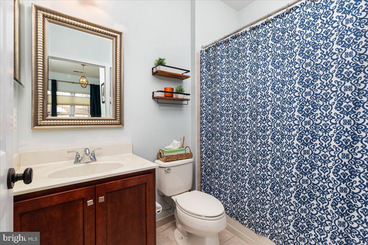 25436 South Riding Boulevard, Unit 2H Chantilly, VA 20152 - Photo 4 of 26 a bathroom with a granite countertop toilet a sink a mirror and a shower