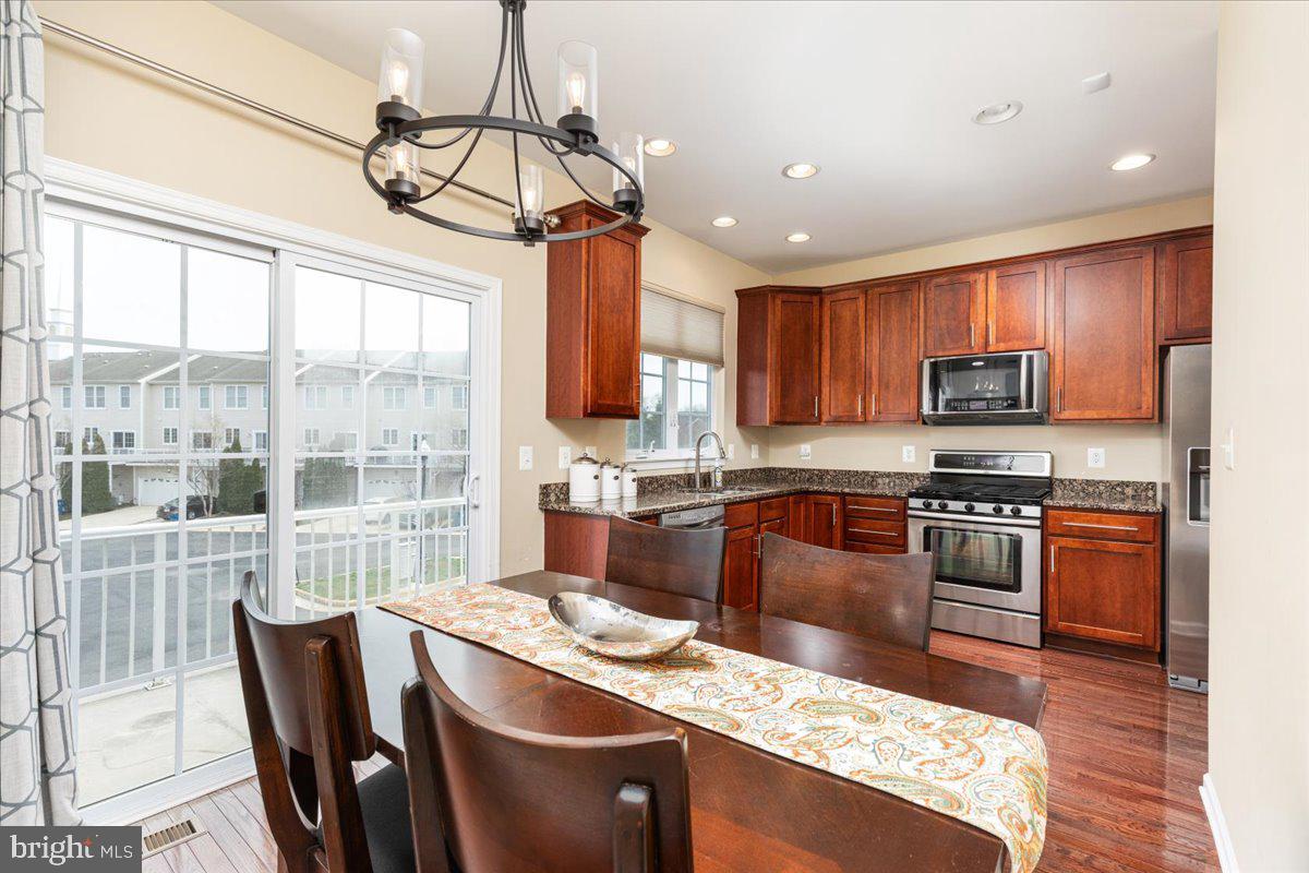 25436 South Riding Boulevard, Unit 2H Chantilly, VA 20152 - Photo 7 of 26 a kitchen with stainless steel appliances granite countertop a stove top oven a sink dishwasher a dining table and chairs with wooden floor