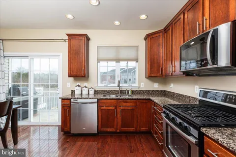 a kitchen with stainless steel appliances granite countertop wooden cabinets stove top oven and sink