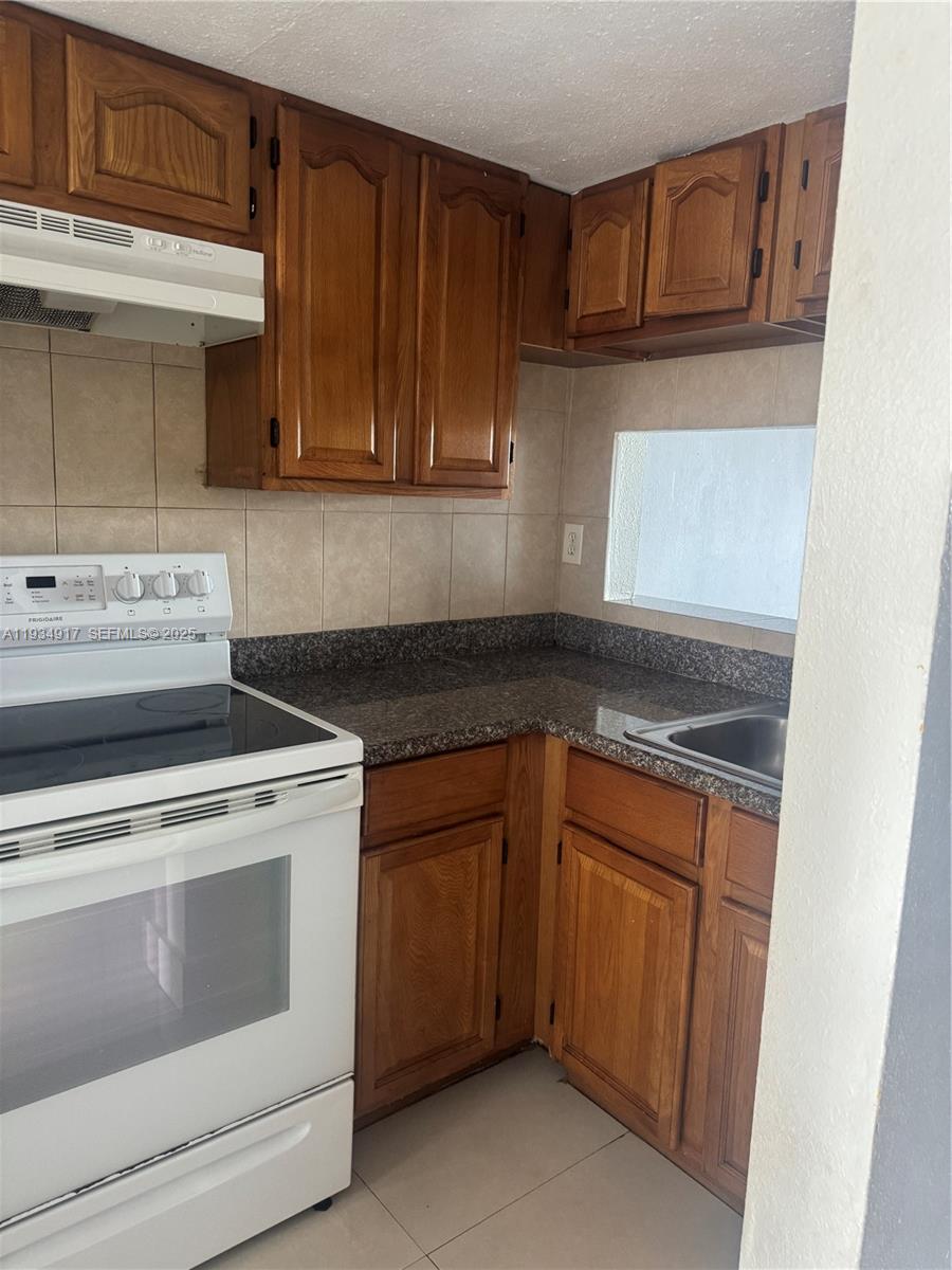 1550 West 7th Court, Unit 23 Hialeah, FL 33010 - Photo 8 of 8 a kitchen with granite countertop cabinets stainless steel appliances and a sink
