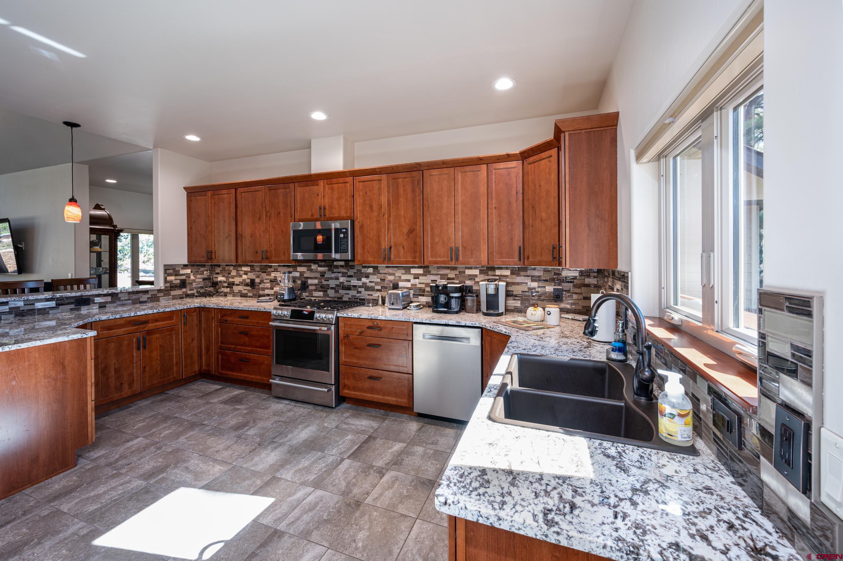 180 Ridge Road Durango, CO 81303 - Photo 11 of 35 a kitchen with stainless steel appliances kitchen island granite countertop wooden cabinets and a stove