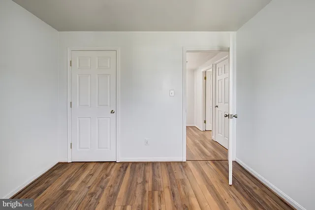 a view of an empty room with wooden floor and closet