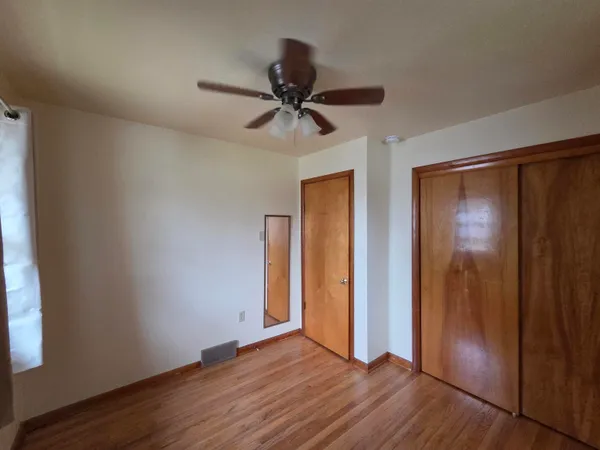an empty room with wooden floor closet and windows
