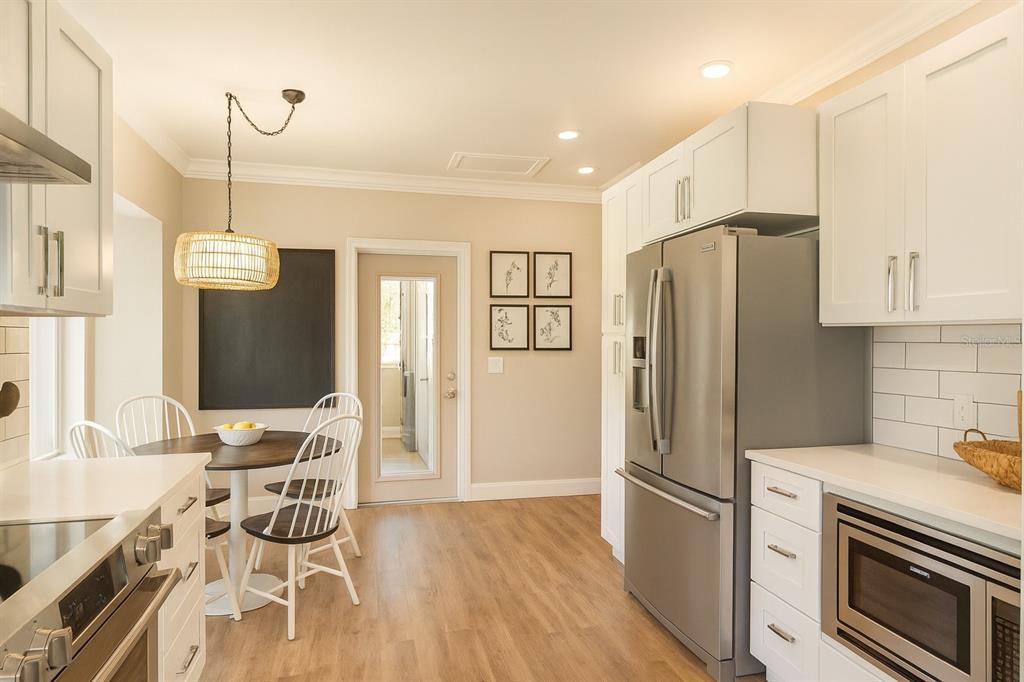 21135 Peckham Avenue Mount Dora, FL 32757 - Photo 7 of 39 a kitchen with stainless steel appliances granite countertop a refrigerator a oven a sink and a dining table with wooden floor
