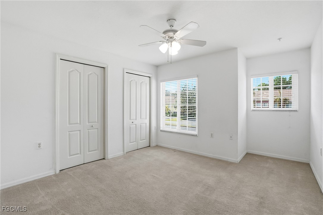 9409 Ivy Brook Run, Unit 1306 Fort Myers, FL 33913 - Photo 24 of 43 an empty room with chandelier fan and windows