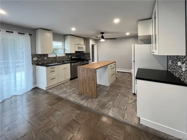 a kitchen with kitchen island granite countertop a stove a sink and a refrigerator