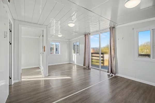 a view of an empty room with wooden floor and a window