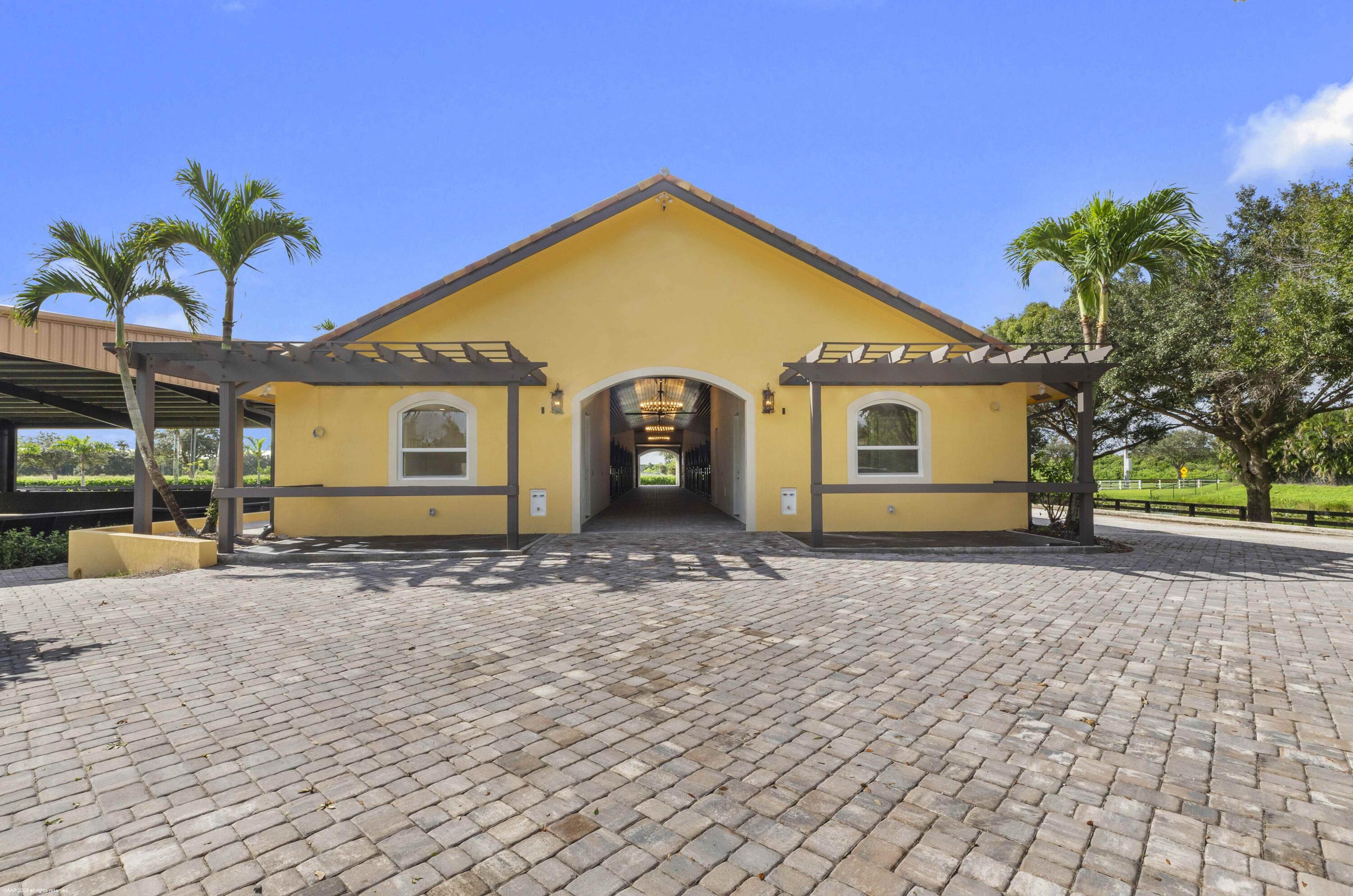 4985 Stables Way Wellington, FL 33414 - Photo 70 of 79 a view of a house with a patio and a yard