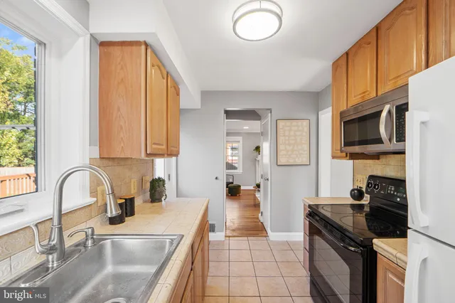 a kitchen with stainless steel appliances granite countertop a sink a stove top oven a chimney a counter space and a window