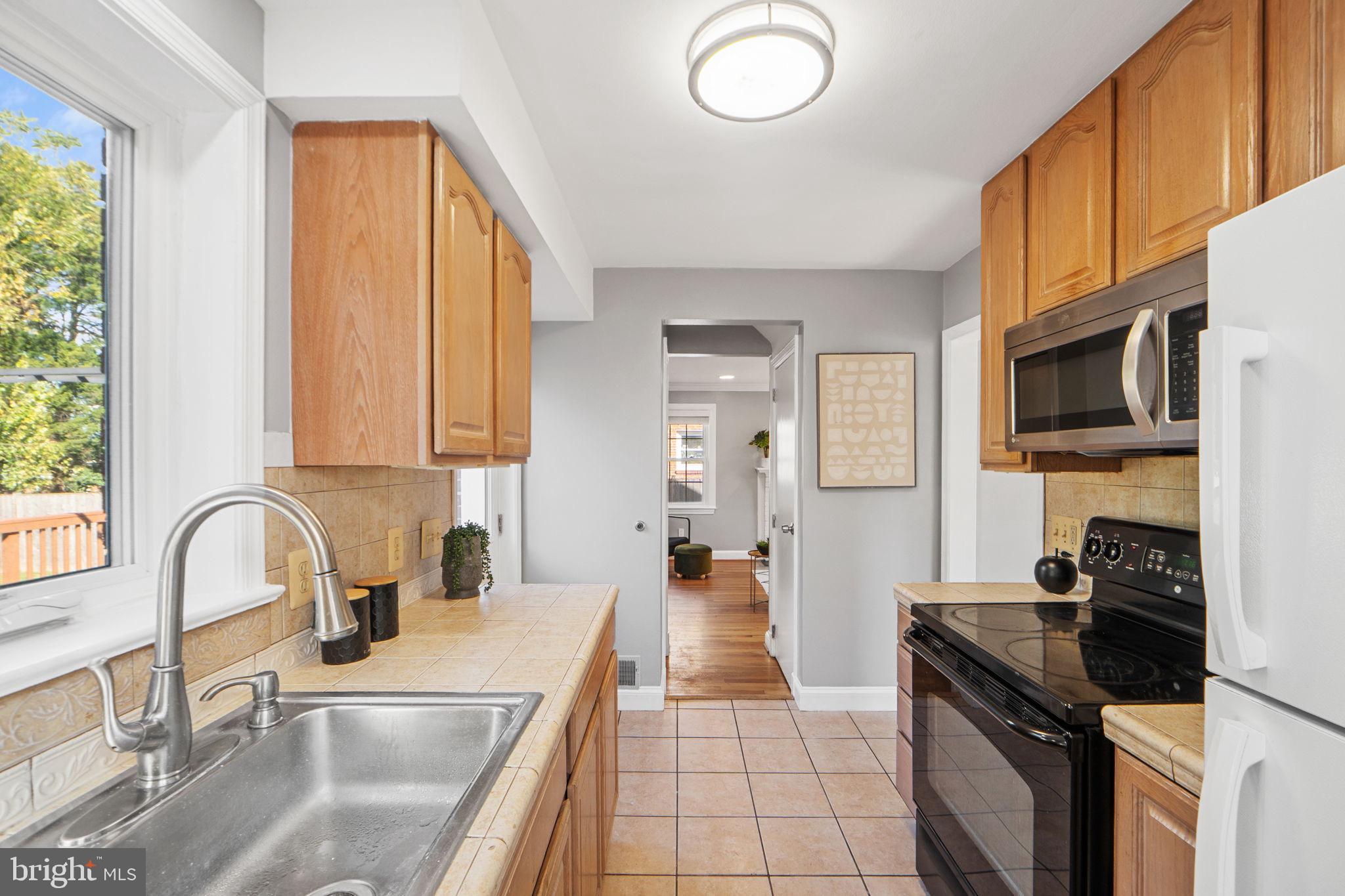 2405 Homestead Drive Silver Spring, MD 20902 - Photo 13 of 43 a kitchen with stainless steel appliances granite countertop a sink a stove top oven a chimney a counter space and a window