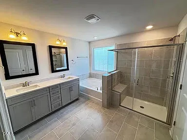 a bathroom with a double vanity sink mirror and bathtub