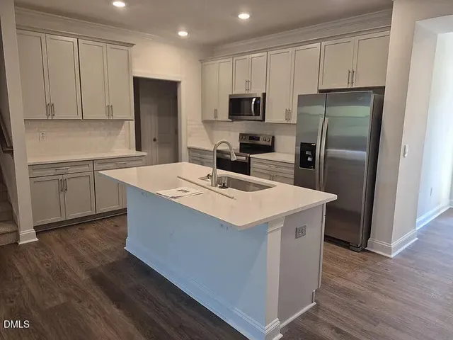 a kitchen with a refrigerator a microwave a sink and cabinets