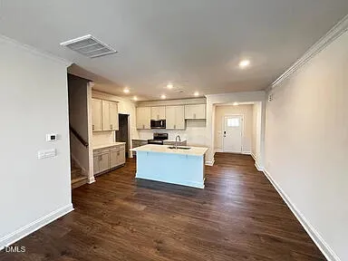 a large kitchen with a refrigerator and wooden floor