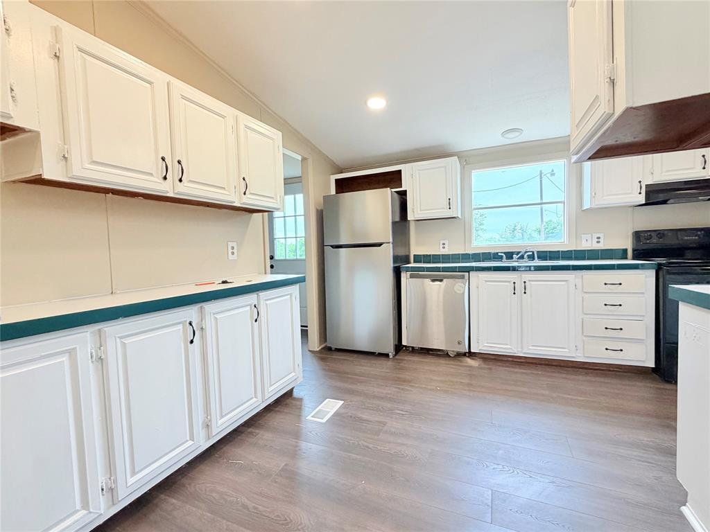 9721 Limestone Joshua, TX 76058 - Photo 13 of 36 a kitchen with granite countertop white cabinets white stainless steel appliances and wooden floors