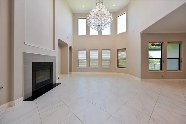 a view of an empty room with chandelier and fireplace
