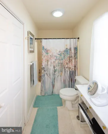 a bathroom with a granite countertop sink a toilet a mirror and shower curtain