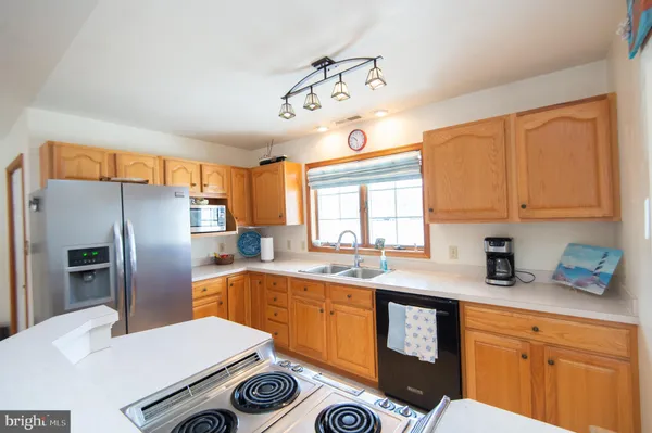 a kitchen with stainless steel appliances a sink a stove a refrigerator cabinets and a window