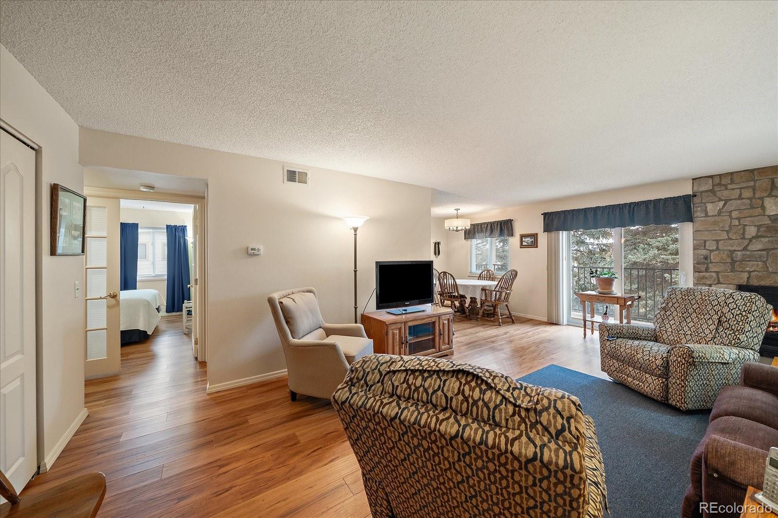 471 South Kalispell Way, Unit 101 Aurora, CO 80017 - Photo 4 of 27 a living room with furniture a large window and a wooden floor
