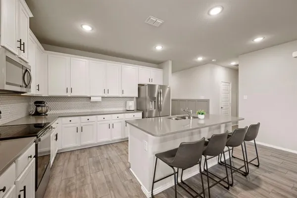 a kitchen with stainless steel appliances granite countertop a table chairs sink and cabinets