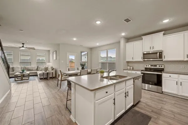 a kitchen with stainless steel appliances granite countertop a sink dishwasher a stove and a refrigerator with wooden floor