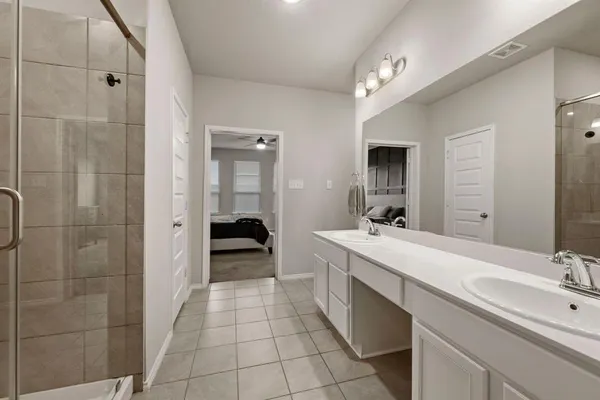 a en suite bathroom with a double vanity sink a mirror and a shower