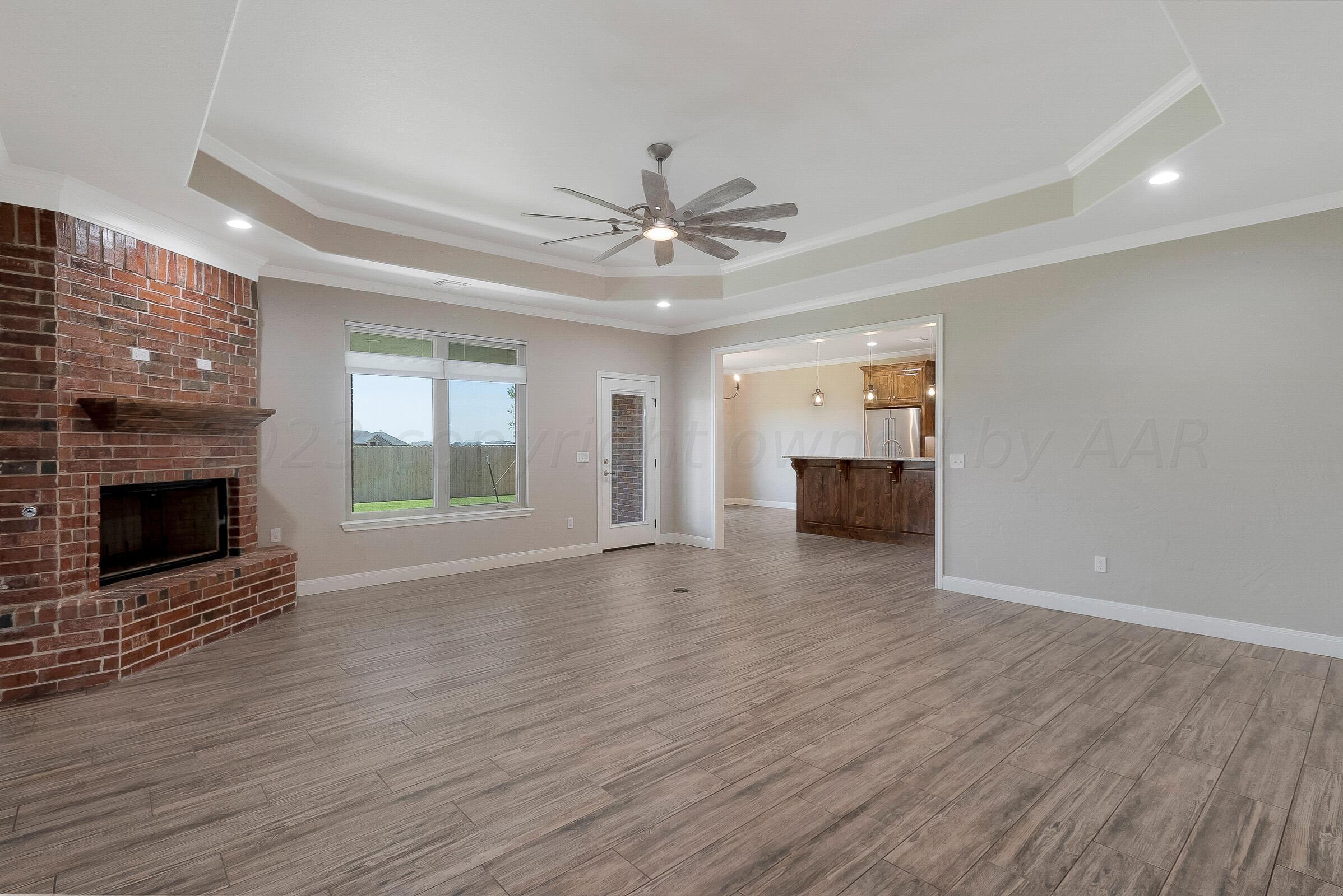 9289 Clinton Glen Road Amarillo, TX 79119 - Photo 6 of 27 a view of a livingroom with a fireplace a ceiling fan and wooden floor