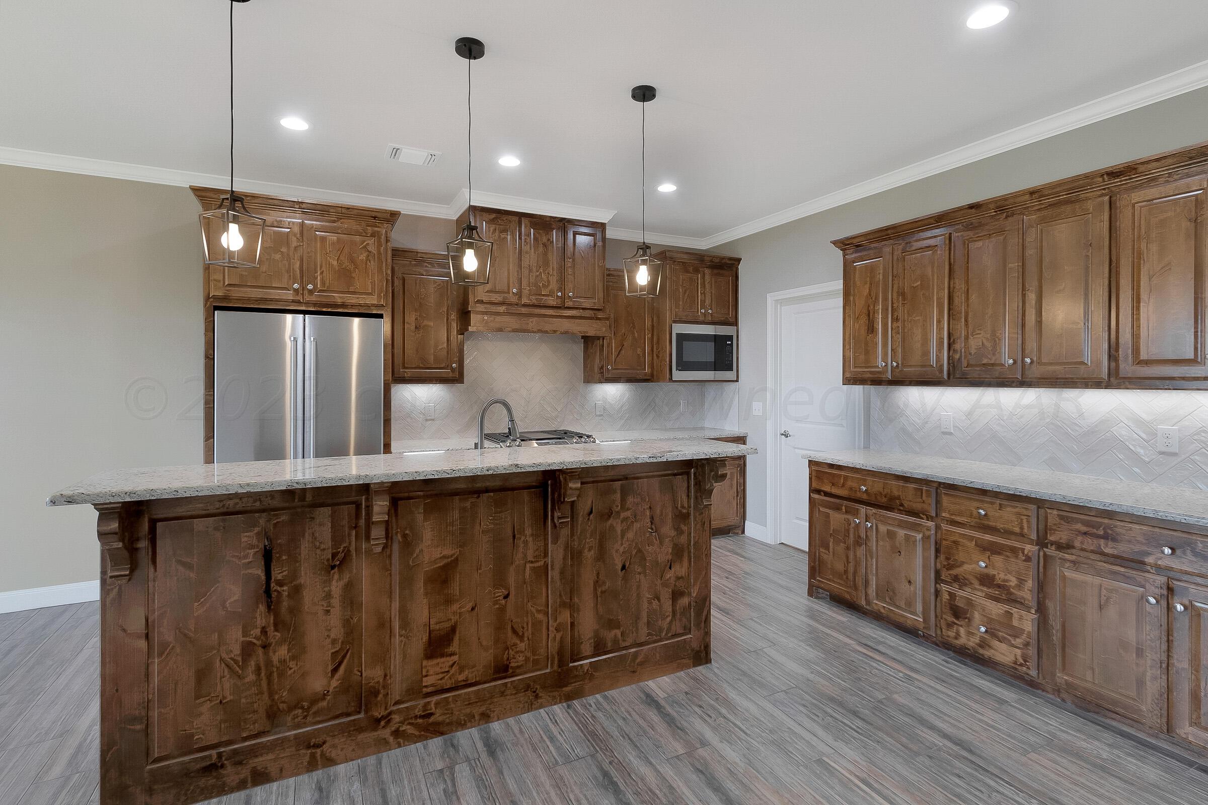 9289 Clinton Glen Road Amarillo, TX 79119 - Photo 7 of 27 a large kitchen with stainless steel appliances granite countertop a large stove a sink dishwasher and a refrigerator with wooden floor