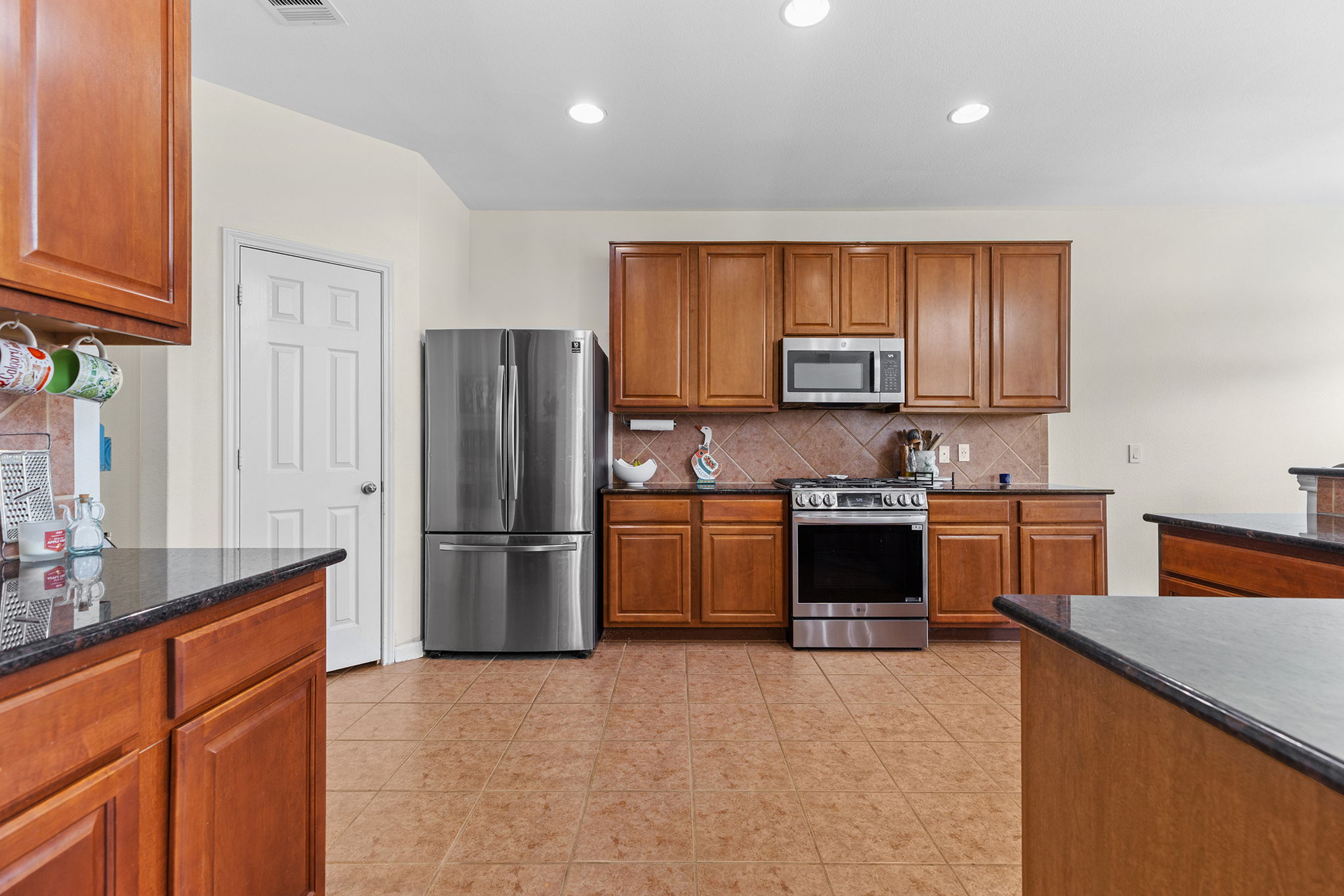 3517 Shiraz Loop Round Rock, TX 78665 - Photo 12 of 40 Kitchen featuring wood cabinetry, stainless steel appliances, dark countertops, and ceramic tile flooring